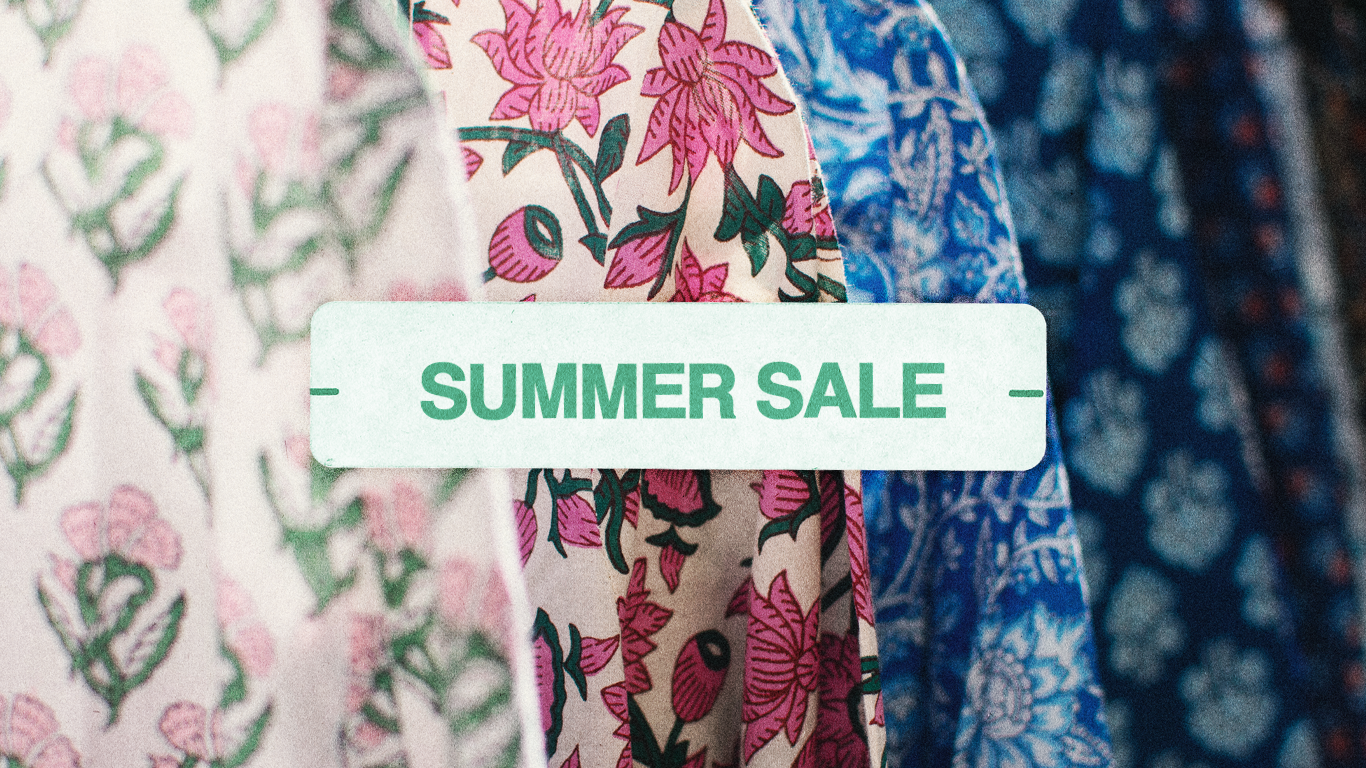 close up of multiple tunics and a white tunic with pink flowers in focus